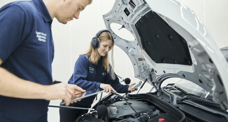 A man and a woman inspect the engine of a car