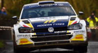 A head-on photo of a yellow, blue and white Volkswagen Polo rally car